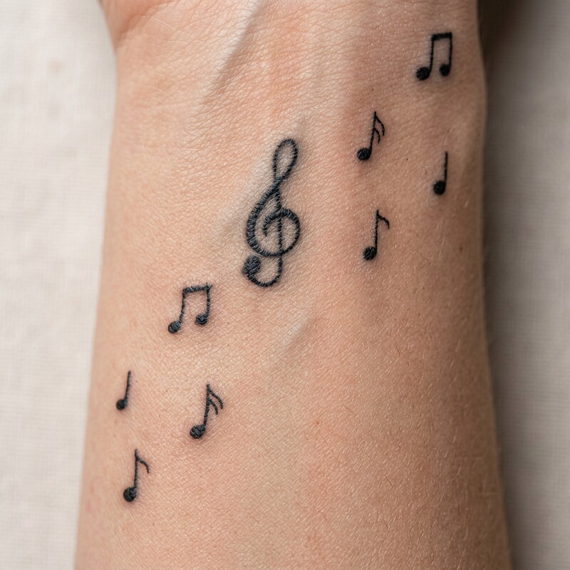 Antes — tatuagem de notas musicais no pulso
